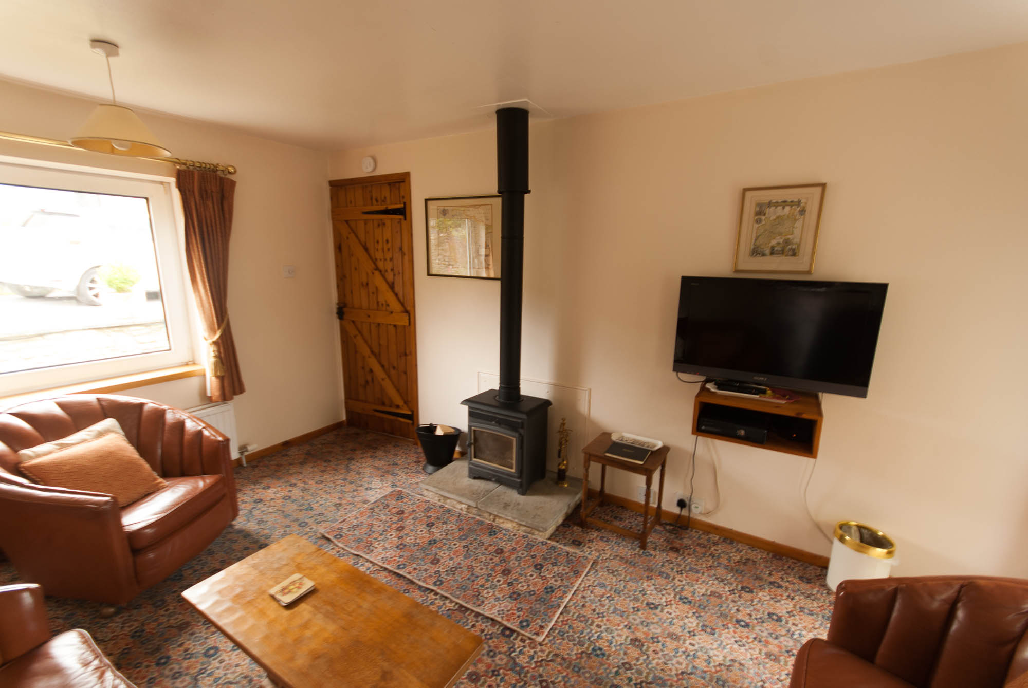 View of the lounge showing the wood burning stove and television.
